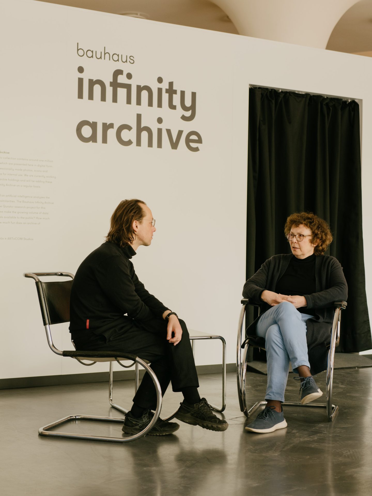 Foto von Annemarie Jaeggi und Philipp Hindahl, wie sie sich auf Stühlen im temporary bauhaus-archiv gegenübersitzen.