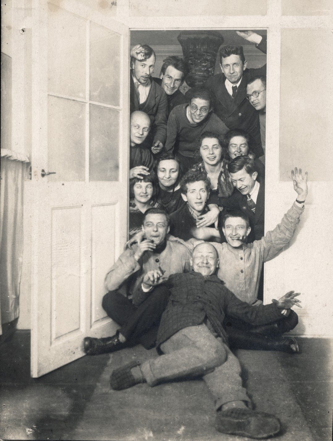 Schwarz-Weiß-Foto einer Gruppe Bauhaus-Studierender, die in einem Türrahmen stehen, sitzen, liegen.