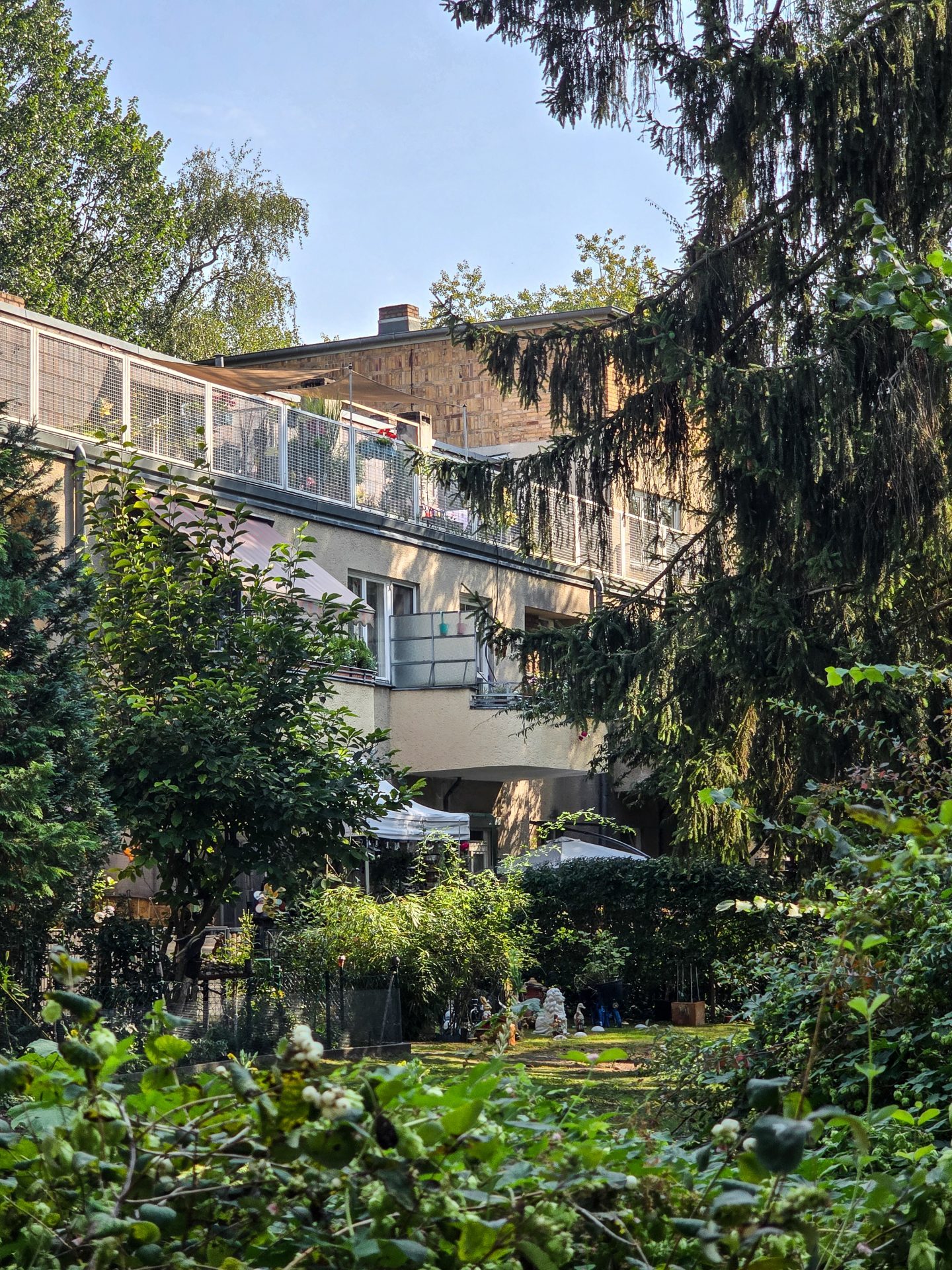 Moderner Gebäudekomplex, umgeben von üppigem Grün und Bäumen in einem einladenden Garten.