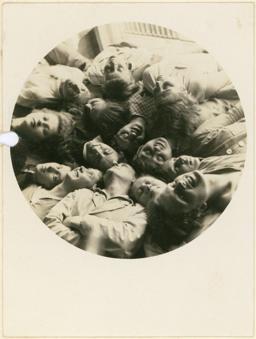 Schwarz-Weiß-Fotografie, Gruppennahaufnahme lächelnder Studierender, die im Kreis liegen und den Kopf zurücklehnen. Vintage print.