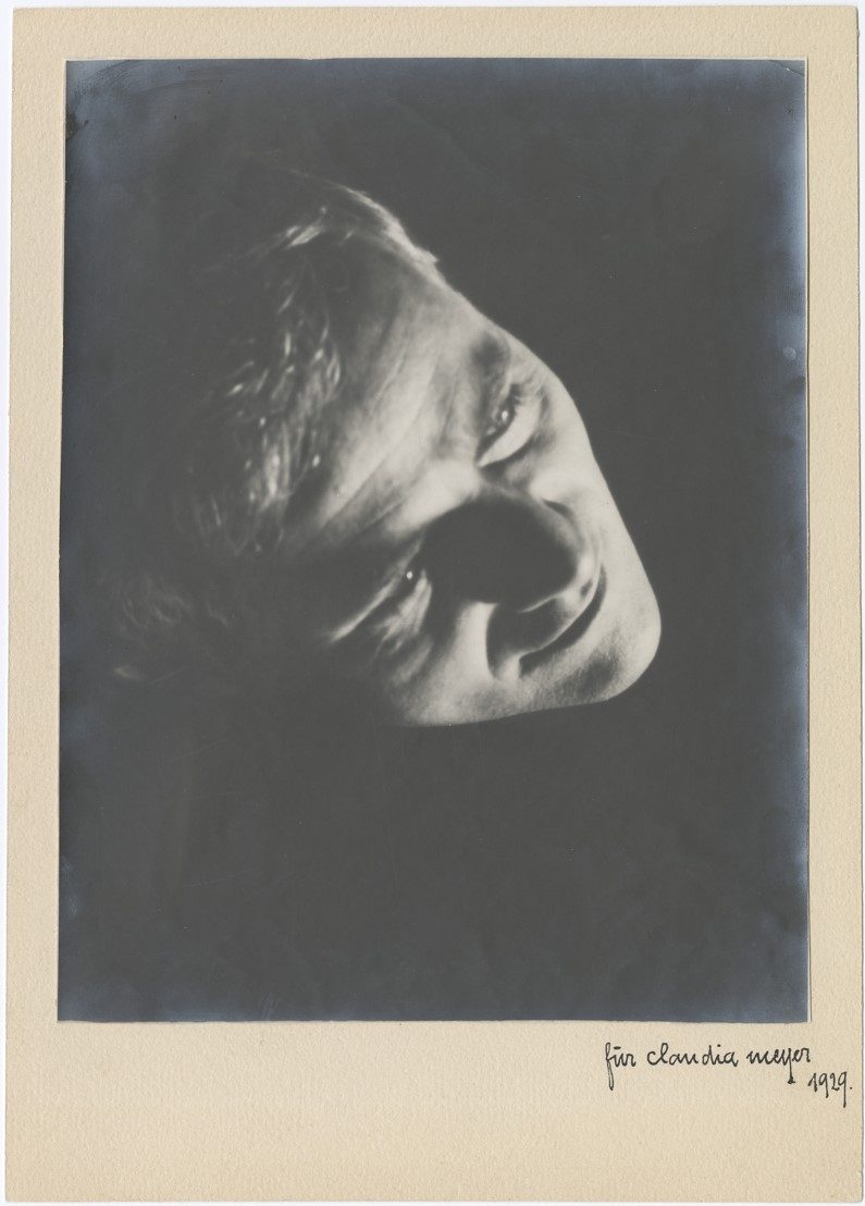 Scan einer Schwarz-Weiß-Fotografie einer Person, die leicht nach oben schaut. Licht fällt ins Gesicht, der Rest ist dunkel.
