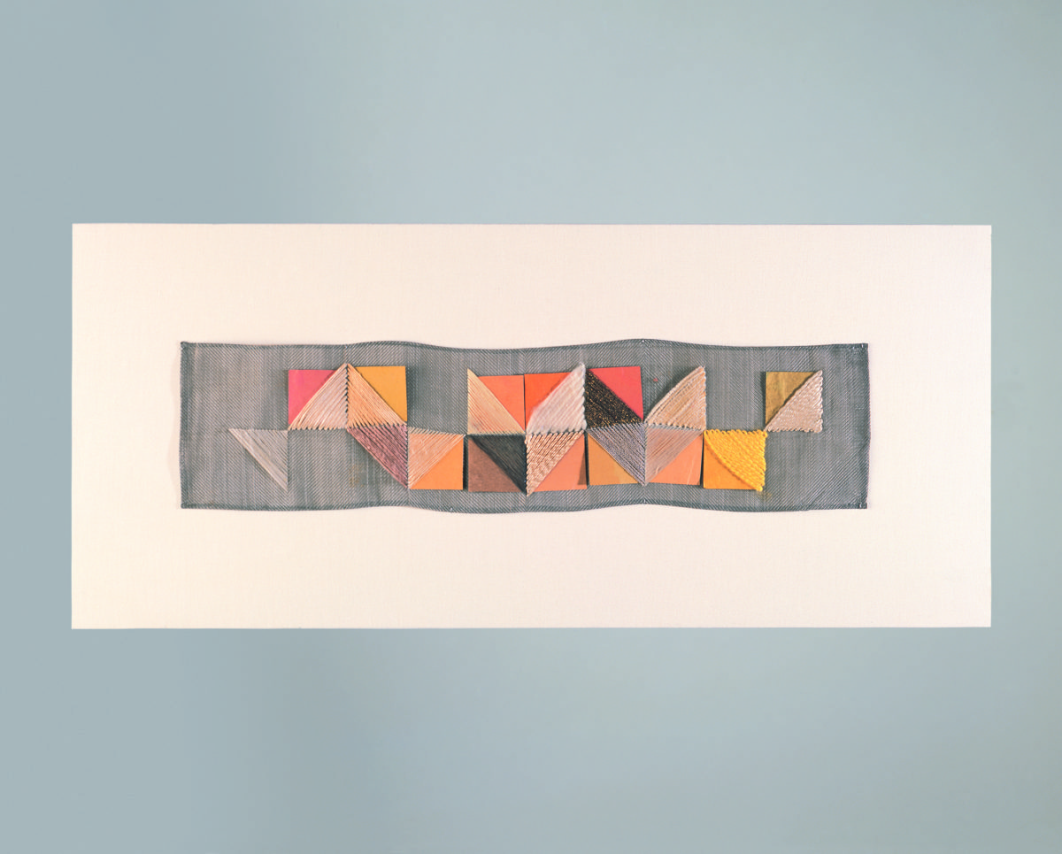 Abstract textile composition with geometric patterns in warm colors on a neutral background.