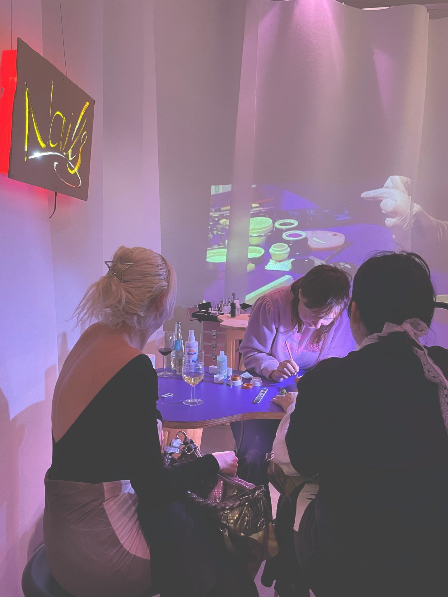 Creative event with two guests watching an artist at a table, with projection lights in the background.