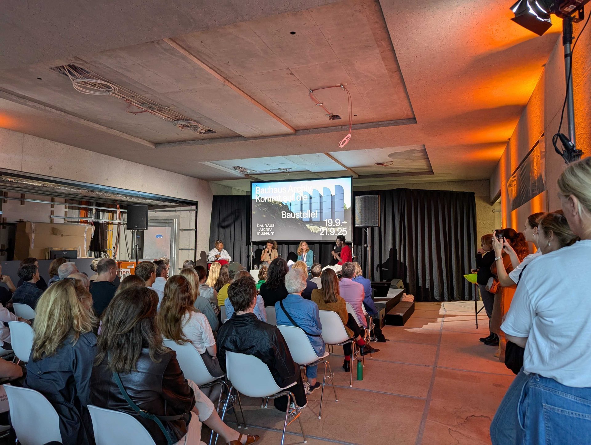 Veranstaltung im Bauhaus-Archiv mit Publikum, Podiumsdiskussion und großem Bildschirm im Hintergrund.