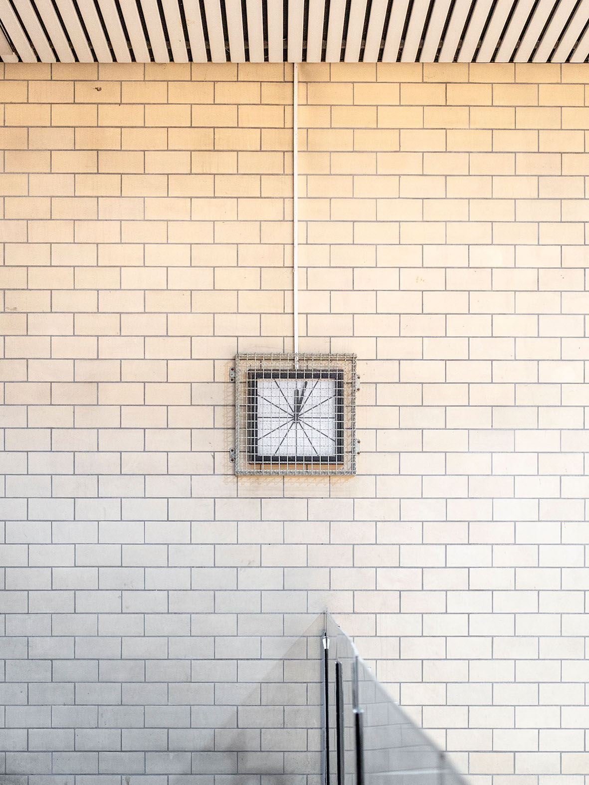 Minimalistisches Bild einer Wand mit rechteckigem Rahmen und grafischem Motiv. Helle Fliesen im Hintergrund.