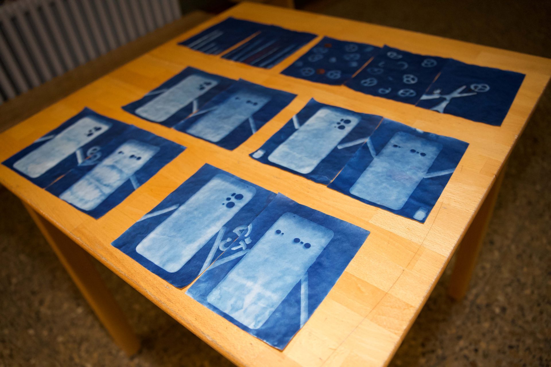 Auf einem Holztisch liegen mehrere blaue Folien mit transparenten Motiven und Mustern.