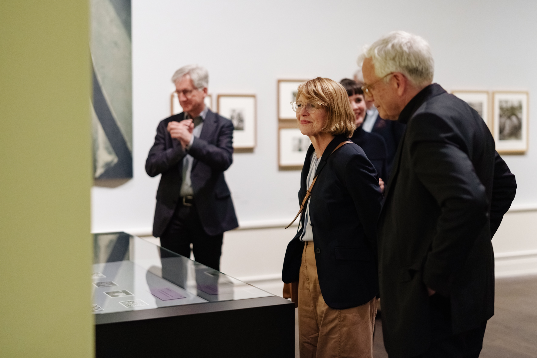 Besucher betrachten Kunstwerke im Museum, tief im Gespräch und mit einem Fokus auf die Ausstellungsstücke.