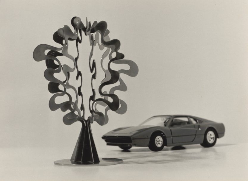 Moderne Skulptur und ein Modellauto in schwarz-weißem Setting. Kunst trifft Automobildesign.